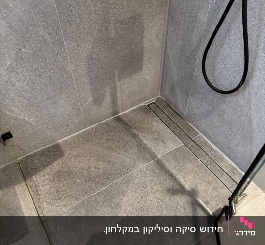 רצפת מקלחת עם אריחים אפורים וראש מקלחת